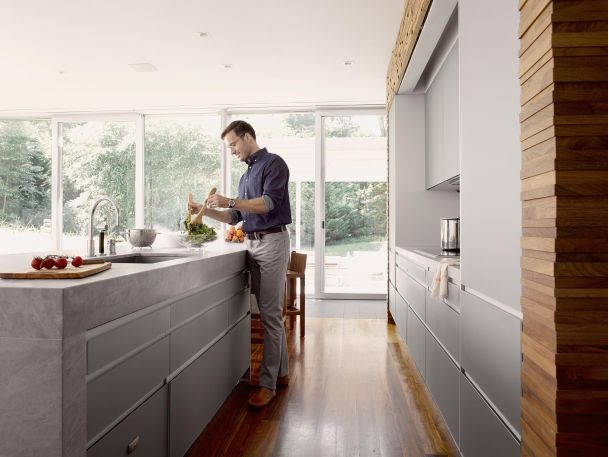 Man preparing a salad in a grey kitchen