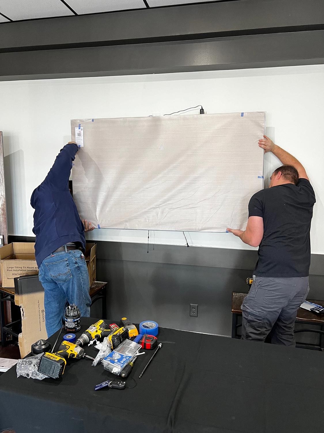 Men installing screen on wall