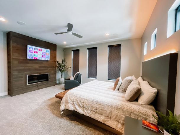 Closed shades and tv hanging in a wooden accent wall with ceiling lighting and speakers